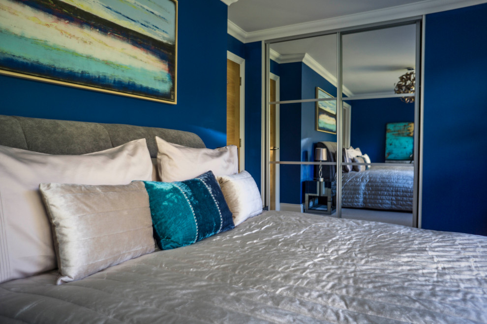 This is an example of a mid-sized contemporary master bedroom in Kent with blue walls, carpet and beige floor.