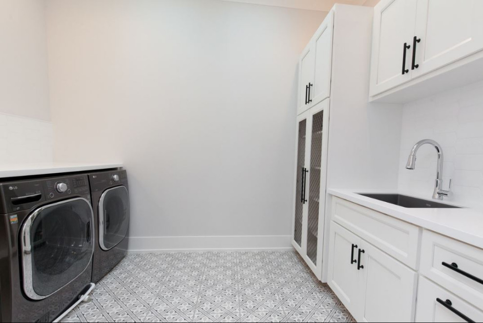 Large country dedicated laundry room in Chicago with an undermount sink, shaker cabinets, white cabinets, quartz benchtops, white splashback, mosaic tile splashback, white walls, porcelain floors, an integrated washer and dryer, grey floor and white benchtop.