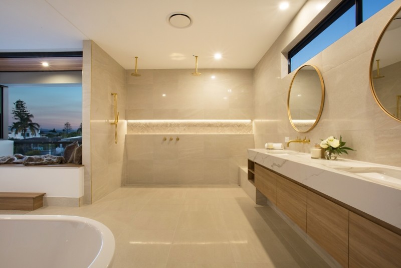 This is an example of a large modern master wet room bathroom in Gold Coast - Tweed with recessed-panel cabinets, medium wood cabinets, a freestanding tub, a wall-mount toilet, beige tile, porcelain tile, white walls, slate floors, an undermount sink, marble benchtops, beige floor and an open shower.