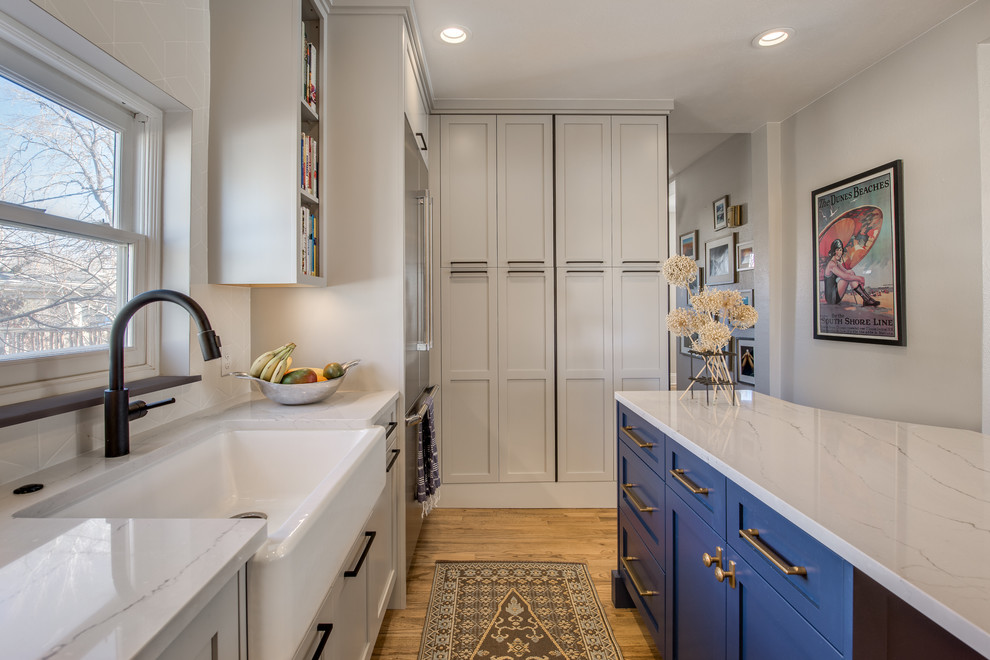 Photo of a small transitional u-shaped separate kitchen in Denver with a farmhouse sink, shaker cabinets, grey cabinets, quartz benchtops, white splashback, ceramic splashback, stainless steel appliances, medium hardwood floors and with island.