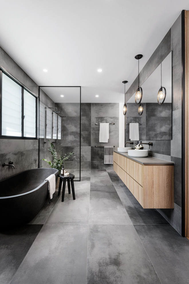 Photo of a large contemporary master bathroom in Brisbane with flat-panel cabinets, light wood cabinets, a freestanding tub, an open shower, gray tile, porcelain tile, porcelain floors, a vessel sink, grey floor, grey benchtops and a floating vanity.