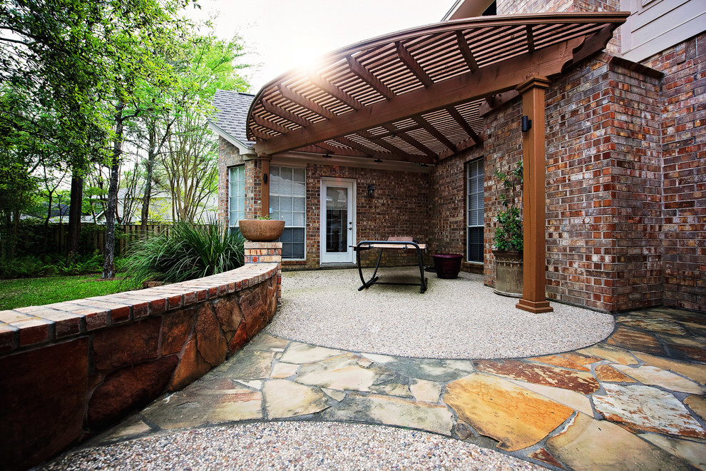 Photo of a mid-sized traditional backyard patio in Houston with a pergola, an outdoor kitchen and natural stone pavers.