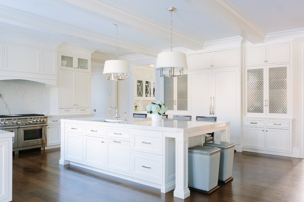 Inspiration for a transitional l-shaped open plan kitchen in Chicago with a drop-in sink, beaded inset cabinets, white cabinets, tile benchtops, white splashback, porcelain splashback, stainless steel appliances, dark hardwood floors, with island, brown floor and white benchtop.