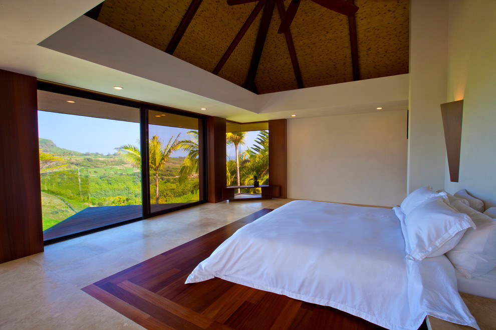 Inspiration for a large tropical master bedroom in Hawaii with beige walls, dark hardwood floors, no fireplace and beige floor.