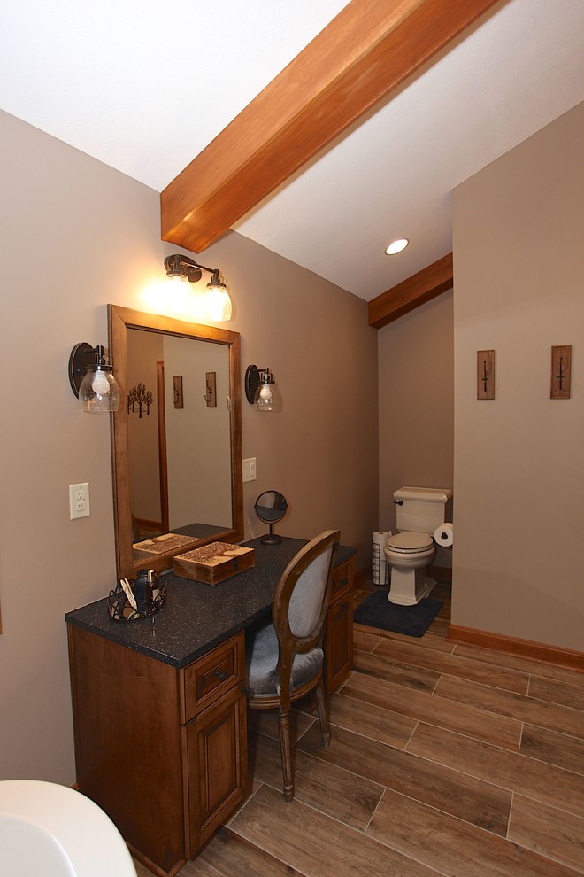 Freestanding bathtub - large rustic master slate tile brown floor freestanding bathtub idea in Indianapolis with brown cabinets, beige walls and an undermount sink