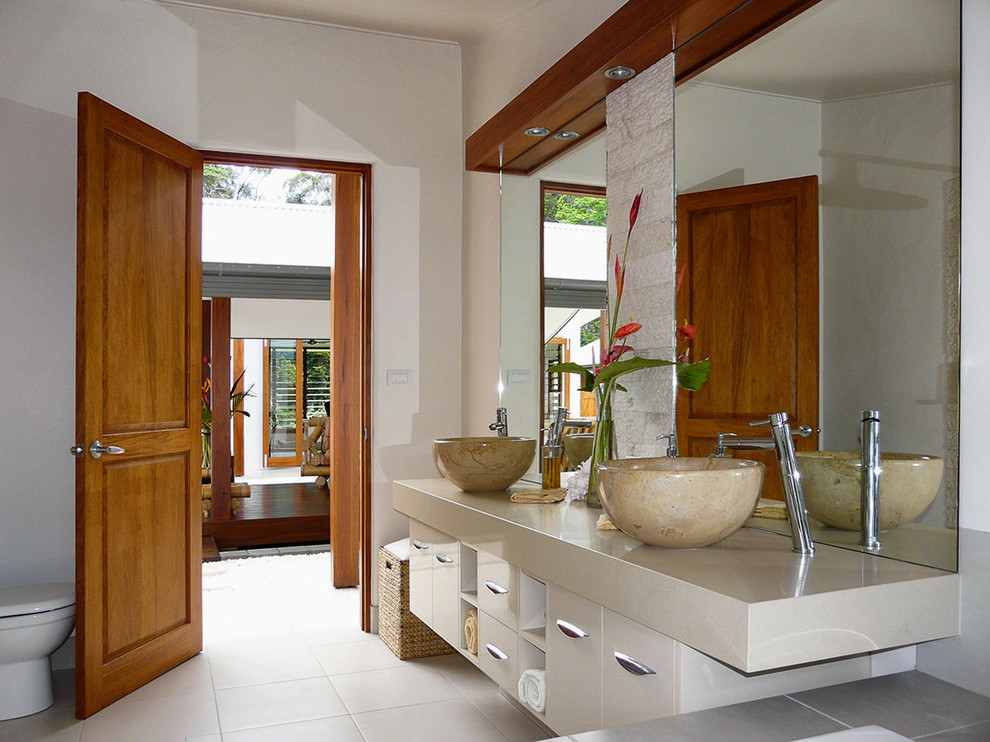 Design ideas for a mid-sized tropical bathroom in Brisbane with a vessel sink, furniture-like cabinets, beige cabinets, engineered quartz benchtops, a one-piece toilet, beige tile, ceramic tile, white walls and porcelain floors.