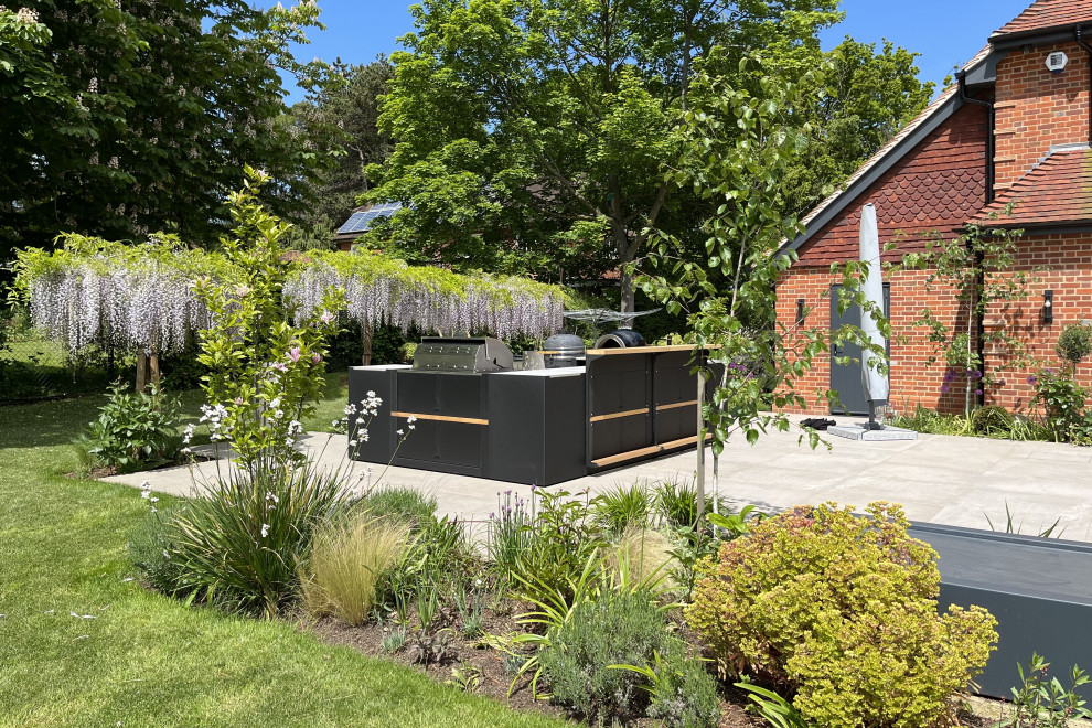 Ejemplo de patio contemporáneo grande sin cubierta en patio trasero con cocina exterior y adoquines de piedra natural