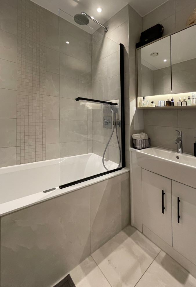 Photo of a scandi bathroom in London with a built-in bath, a shower/bath combination, grey tiles, grey walls, ceramic flooring, grey floors and a single sink.