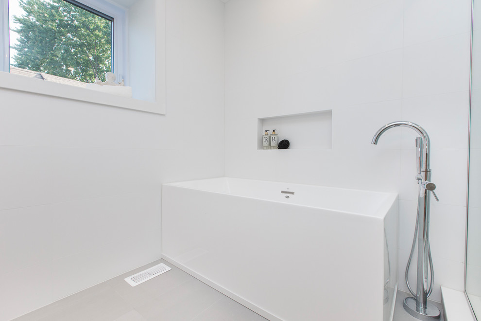 This is an example of a mid-sized modern master bathroom in Ottawa with flat-panel cabinets, light wood cabinets, a freestanding tub, a corner shower, a one-piece toilet, white tile, ceramic tile, white walls, ceramic floors, an undermount sink, engineered quartz benchtops, grey floor, a hinged shower door and white benchtops.