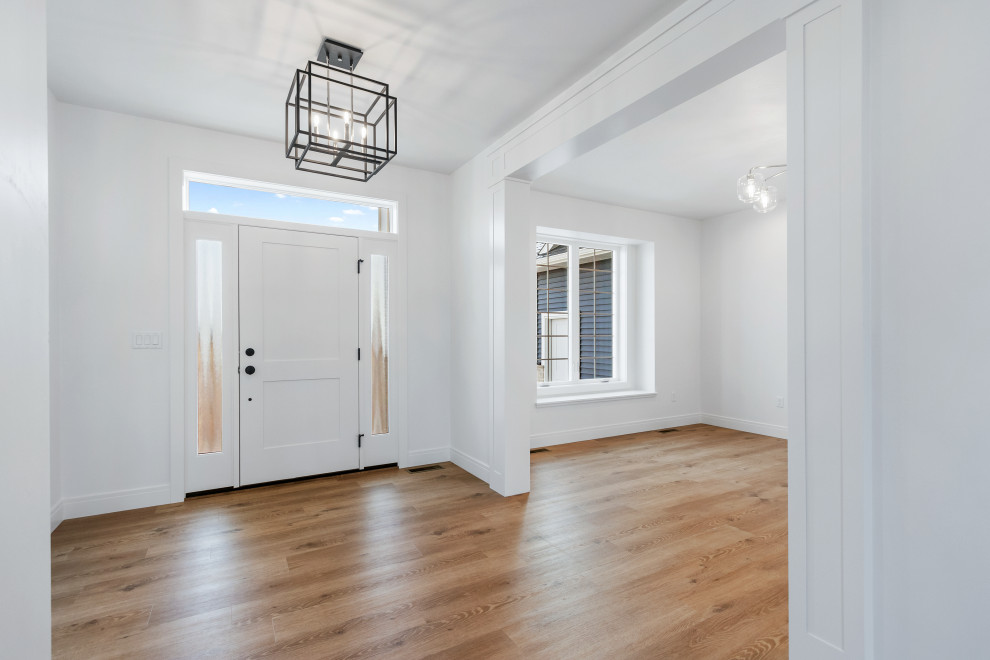 Mid-sized transitional light wood floor and brown floor foyer photo with white walls and a white front door