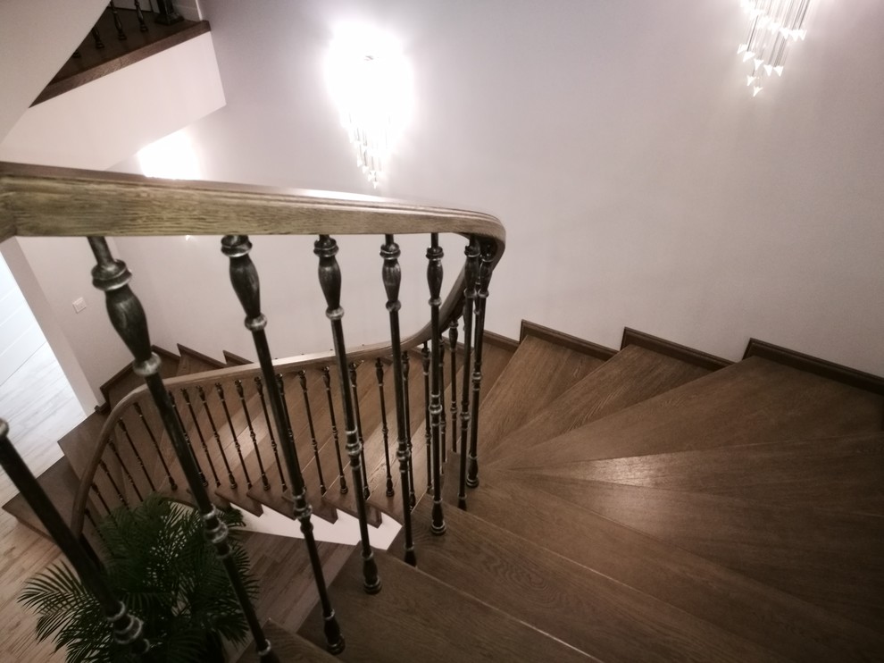 This is an example of a large eclectic wood curved staircase in Moscow with wood risers and mixed railing.