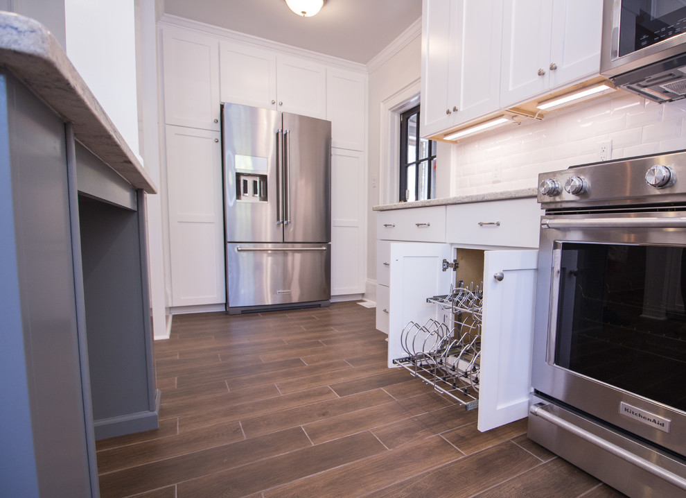 Example of a small u-shaped ceramic tile eat-in kitchen design with an undermount sink, shaker cabinets, white cabinets, quartz countertops, white backsplash, subway tile backsplash, stainless steel appliances, an island and white countertops