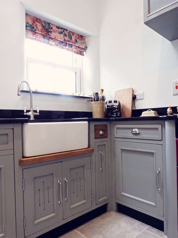 This is an example of a bohemian u-shaped open plan kitchen in Belfast with a belfast sink, grey cabinets and no island.