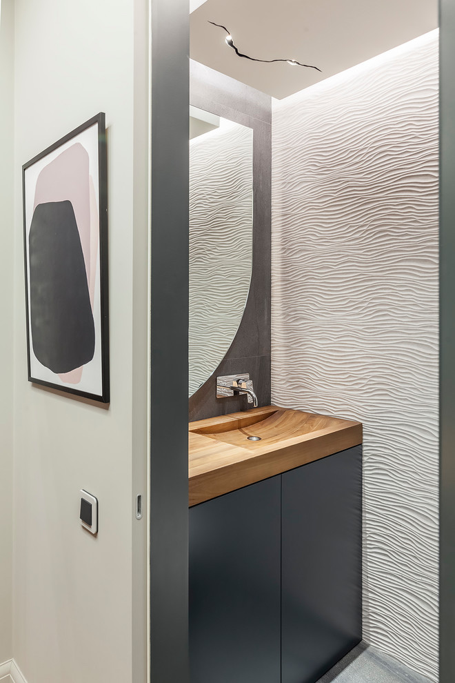 This is an example of a small contemporary powder room in Other with flat-panel cabinets, grey cabinets, white tile, an integrated sink, wood benchtops, grey floor and brown benchtops.