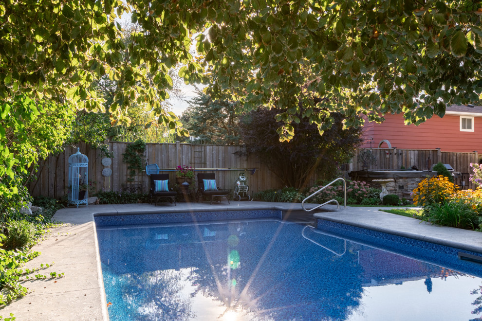 This is an example of a medium sized modern back rectangular swimming pool in Toronto with with pool landscaping and stamped concrete.
