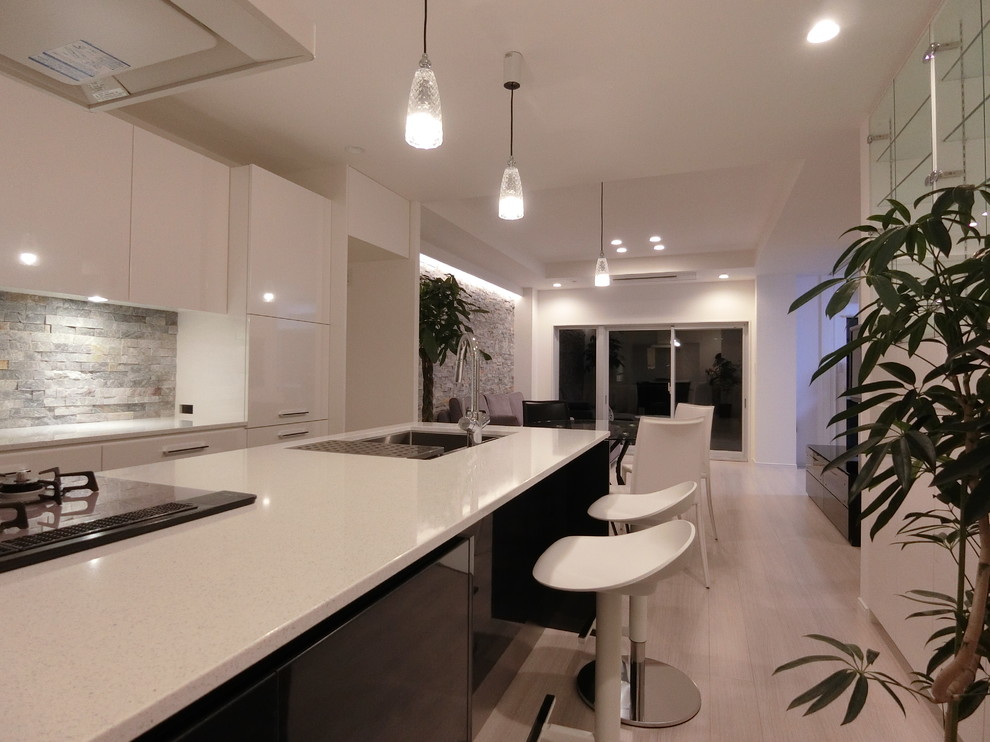 Mid-sized modern galley open plan kitchen in Tokyo with an undermount sink, flat-panel cabinets, black cabinets, quartz benchtops, grey splashback, stone slab splashback, stainless steel appliances, plywood floors, a peninsula and white floor.