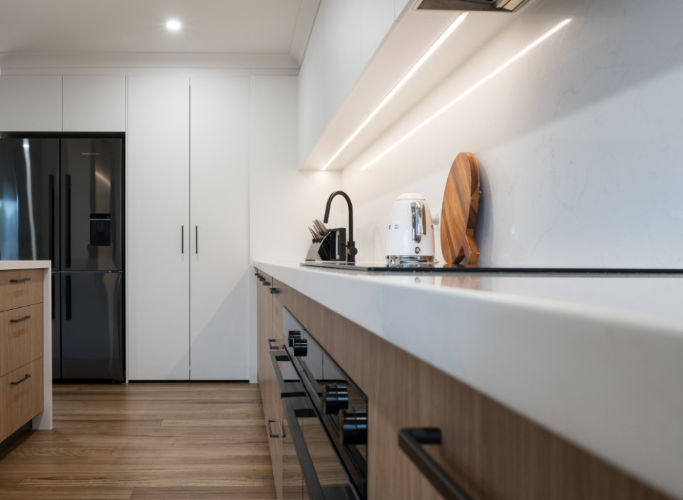 Photo of a mid-sized contemporary kitchen in Melbourne with engineered quartz splashback and black appliances.