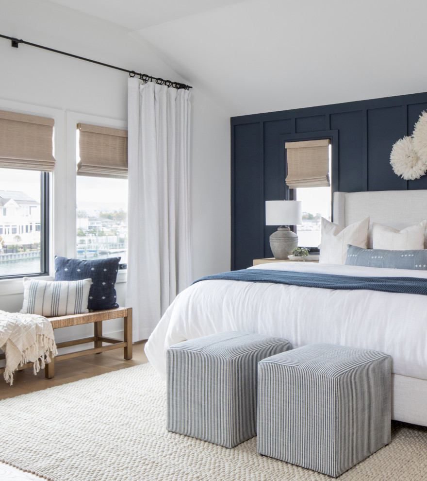 Diseño de dormitorio principal costero de tamaño medio con paredes azules, suelo de madera en tonos medios y panelado