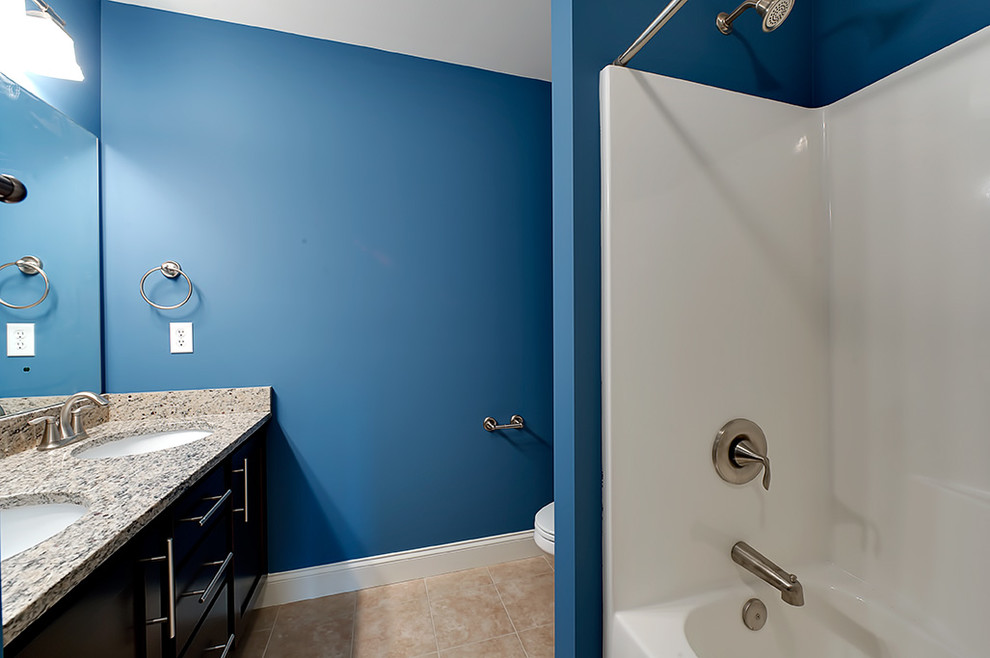 Transitional drop-in bathtub photo with a drop-in sink, flat-panel cabinets, black cabinets and blue walls