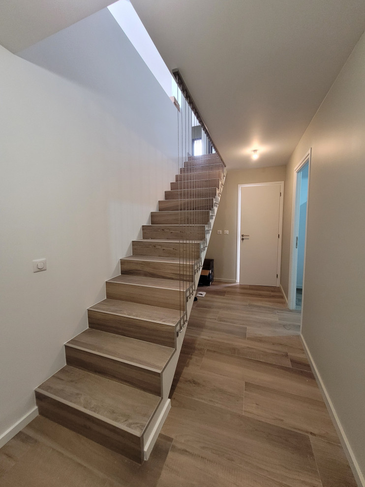 Photo of a mid-sized modern concrete straight staircase in Paris with wood risers and cable railing.