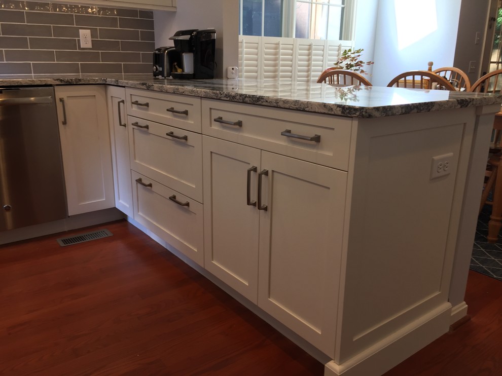Design ideas for a mid-sized transitional u-shaped open plan kitchen in Baltimore with a double-bowl sink, shaker cabinets, white cabinets, quartz benchtops, grey splashback, ceramic splashback, stainless steel appliances, medium hardwood floors, no island, red floor and grey benchtop.