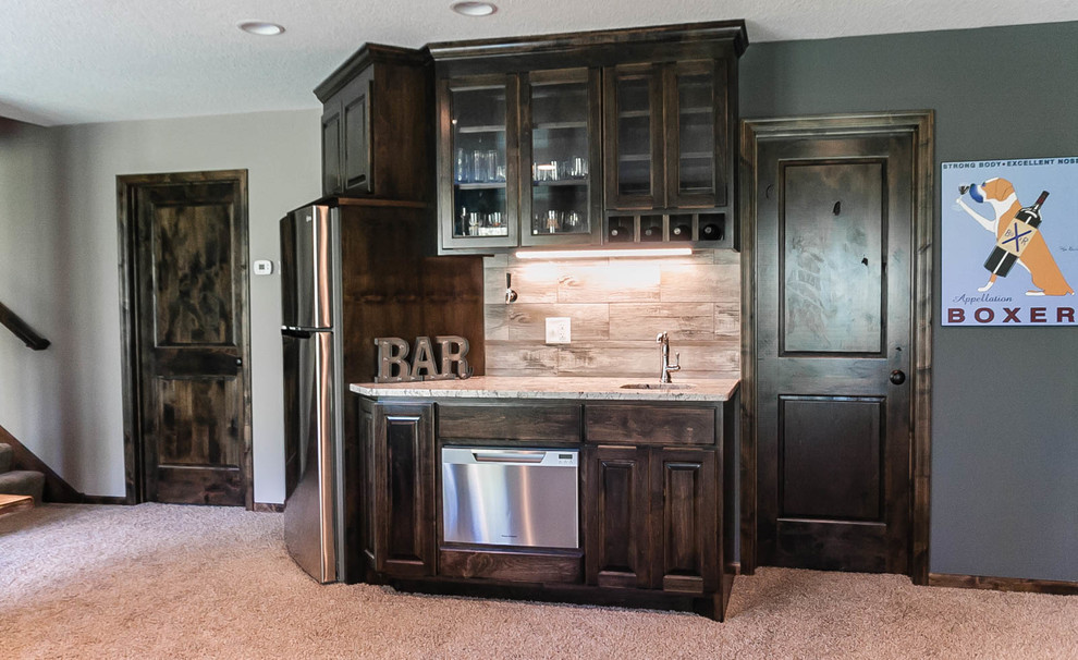 This is an example of a small traditional galley wet bar in Minneapolis with an undermount sink, raised-panel cabinets, dark wood cabinets, granite benchtops, porcelain splashback and carpet.