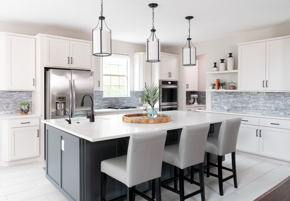 Transitional l-shaped white floor kitchen photo in Austin with an undermount sink, shaker cabinets, white cabinets, gray backsplash, stainless steel appliances, an island and white countertops