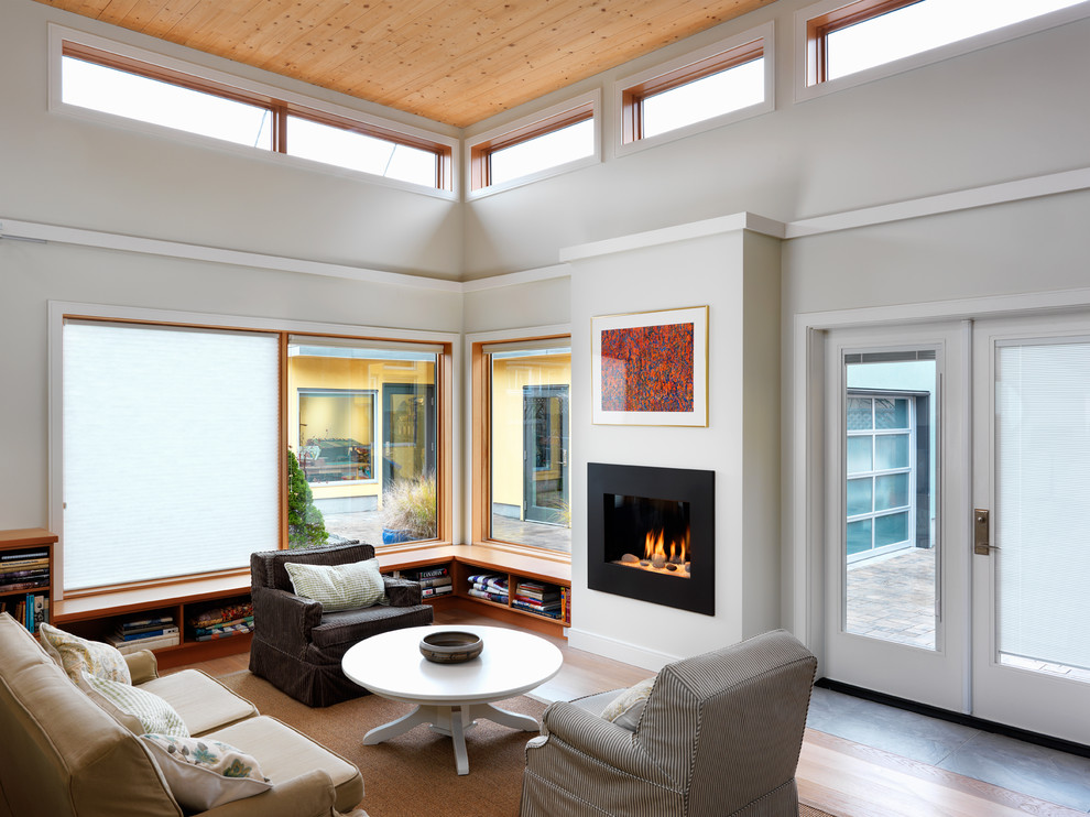 Photo of a contemporary living room in Other with white walls, medium hardwood floors, a standard fireplace and brown floor.