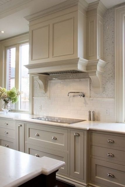 This is an example of a traditional kitchen in New York with flat-panel cabinets, beige cabinets, white splashback, subway tile splashback, stainless steel appliances and with island.