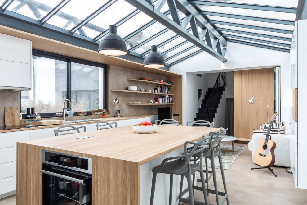 パリにあるコンテンポラリースタイルのおしゃれなキッチン (フラットパネル扉のキャビネット、白いキャビネット、コンクリートの床、グレーの床、ベージュのキッチンカウンター) の写真