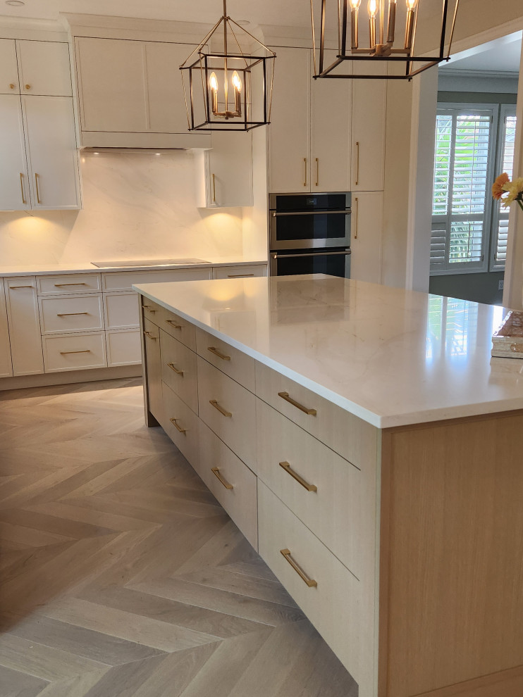 Example of a large transitional light wood floor and beige floor eat-in kitchen design with a farmhouse sink, shaker cabinets, white cabinets, quartzite countertops, white backsplash, quartz backsplash, stainless steel appliances, an island and white countertops