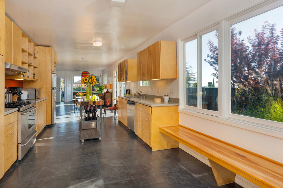 Mid-sized midcentury galley eat-in kitchen in Phoenix with flat-panel cabinets, light wood cabinets, quartz benchtops, stainless steel appliances, slate floors, a double-bowl sink, orange splashback and with island.