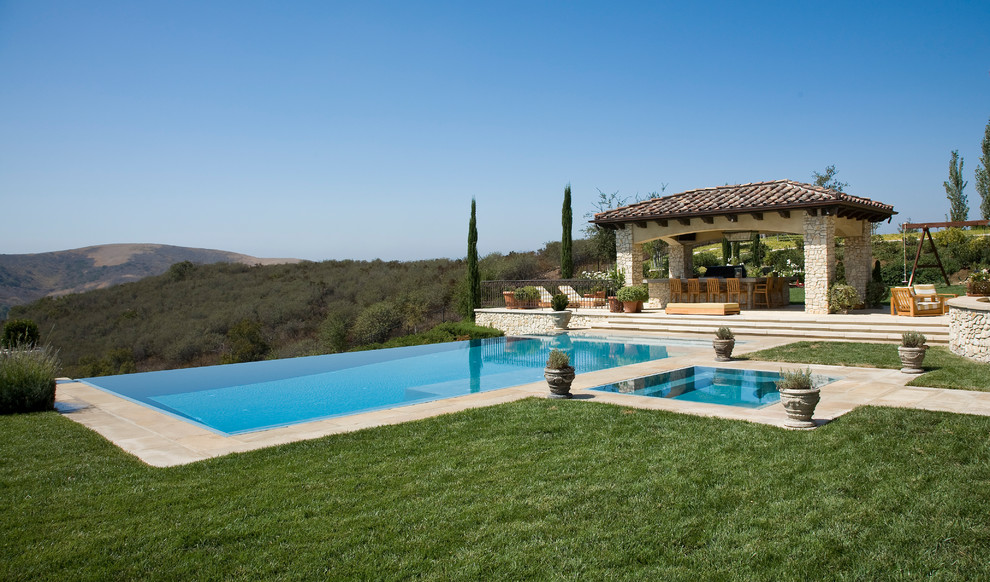Inspiration for a mediterranean backyard rectangular infinity pool in Los Angeles with concrete pavers.