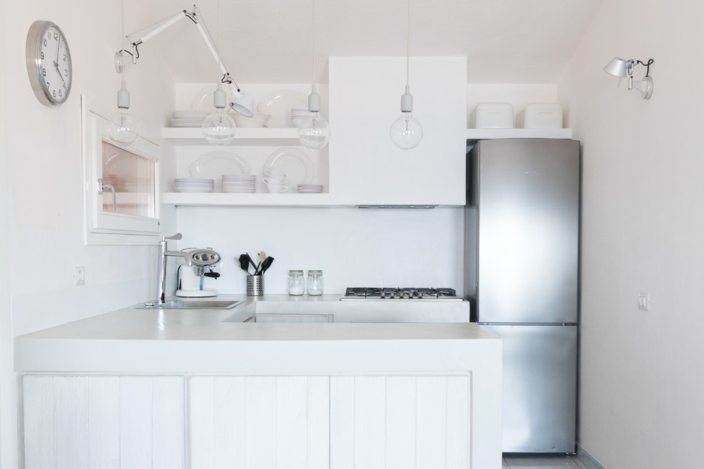 This is an example of a small transitional u-shaped open plan kitchen in Other with raised-panel cabinets, white cabinets, concrete benchtops, grey splashback, white appliances, a peninsula and a drop-in sink.