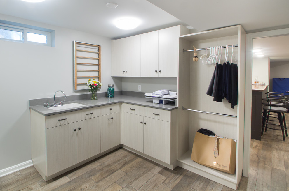 Inspiration for a mid-sized l-shaped dedicated laundry room in Louisville with an undermount sink, flat-panel cabinets, light wood cabinets, concrete benchtops, grey walls, porcelain floors, a side-by-side washer and dryer, beige floor and grey benchtop.