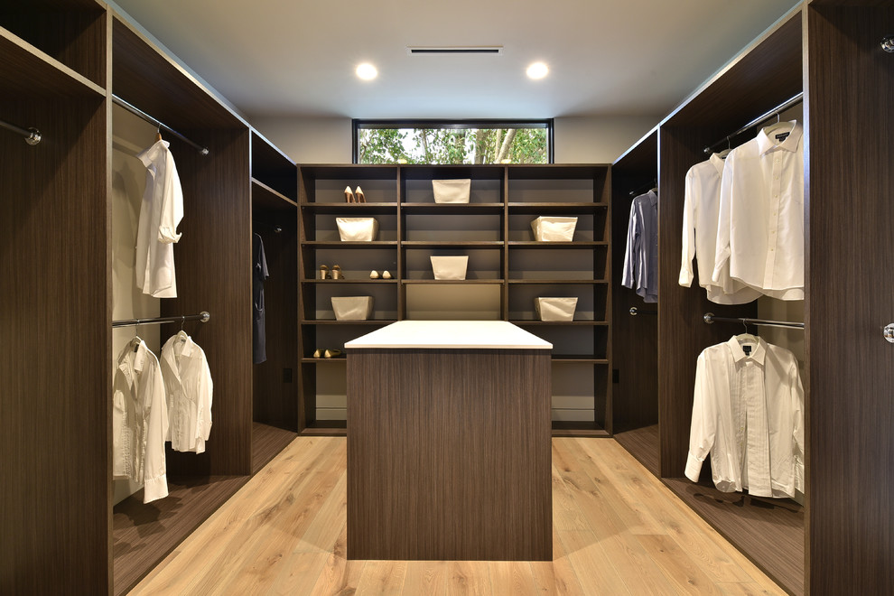 This is an example of a contemporary gender-neutral dressing room in Austin with open cabinets, dark wood cabinets and light hardwood floors.