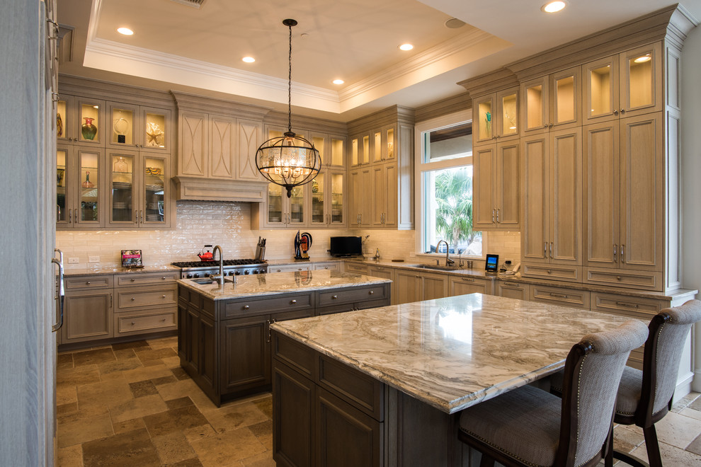 Design ideas for a large transitional u-shaped kitchen in Other with an undermount sink, raised-panel cabinets, brown cabinets, quartzite benchtops, white splashback, subway tile splashback, panelled appliances, travertine floors, multiple islands and beige floor.