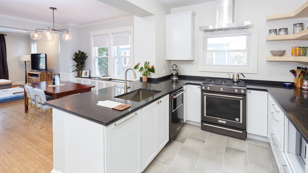 This is an example of a mid-sized transitional u-shaped eat-in kitchen in Baltimore with an undermount sink, shaker cabinets, white cabinets, granite benchtops, white splashback, window splashback, stainless steel appliances, ceramic floors, a peninsula, grey floor and black benchtop.