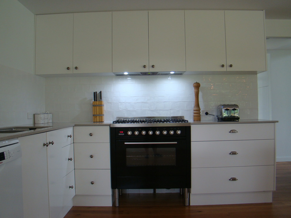 This is an example of a contemporary kitchen in Other with quartz benchtops, white splashback, subway tile splashback, medium hardwood floors, with island and grey benchtop.