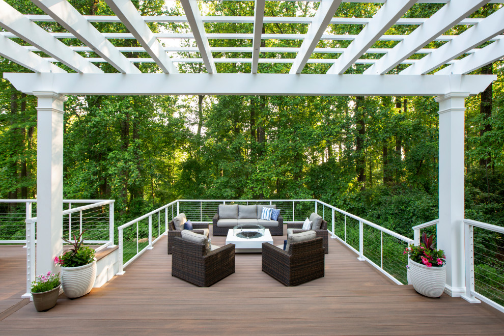 Photo of a large modern backyard and ground level deck in New York with a fire feature, a pergola and cable railing.