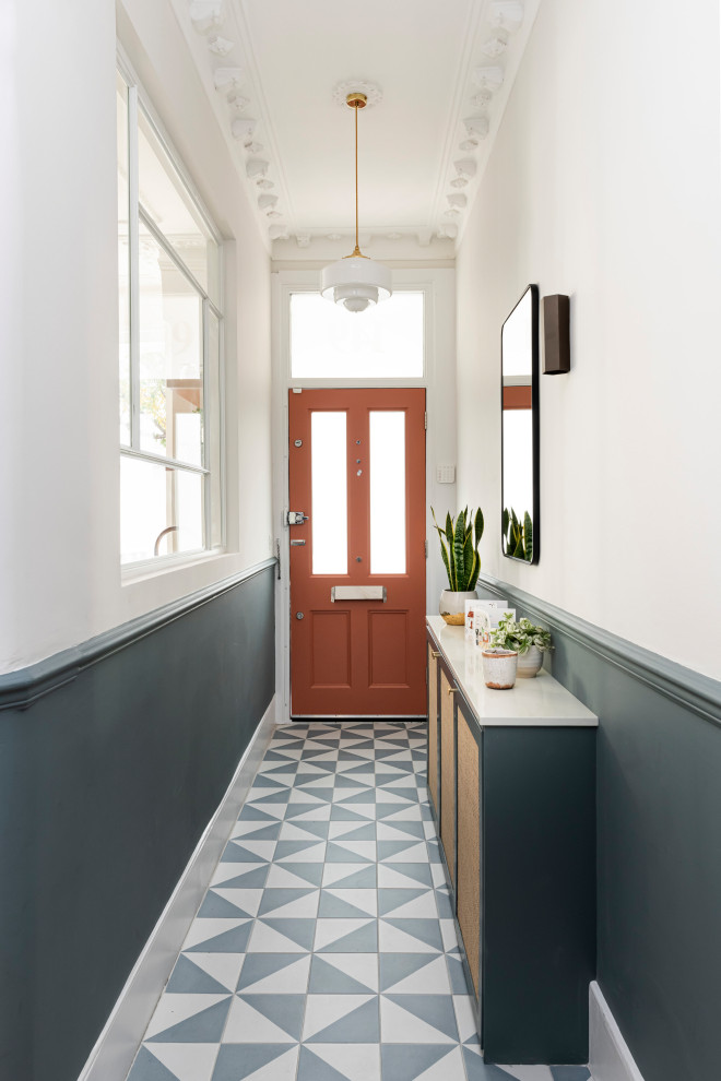 Inredning av en klassisk mellanstor ingång och ytterdörr, med blå väggar, klinkergolv i keramik, en enkeldörr, en röd dörr och blått golv