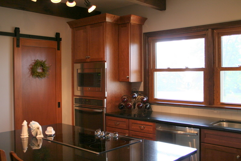 Example of a mid-sized transitional l-shaped medium tone wood floor kitchen design with an undermount sink, recessed-panel cabinets, medium tone wood cabinets, granite countertops, white backsplash, ceramic backsplash, stainless steel appliances and an island
