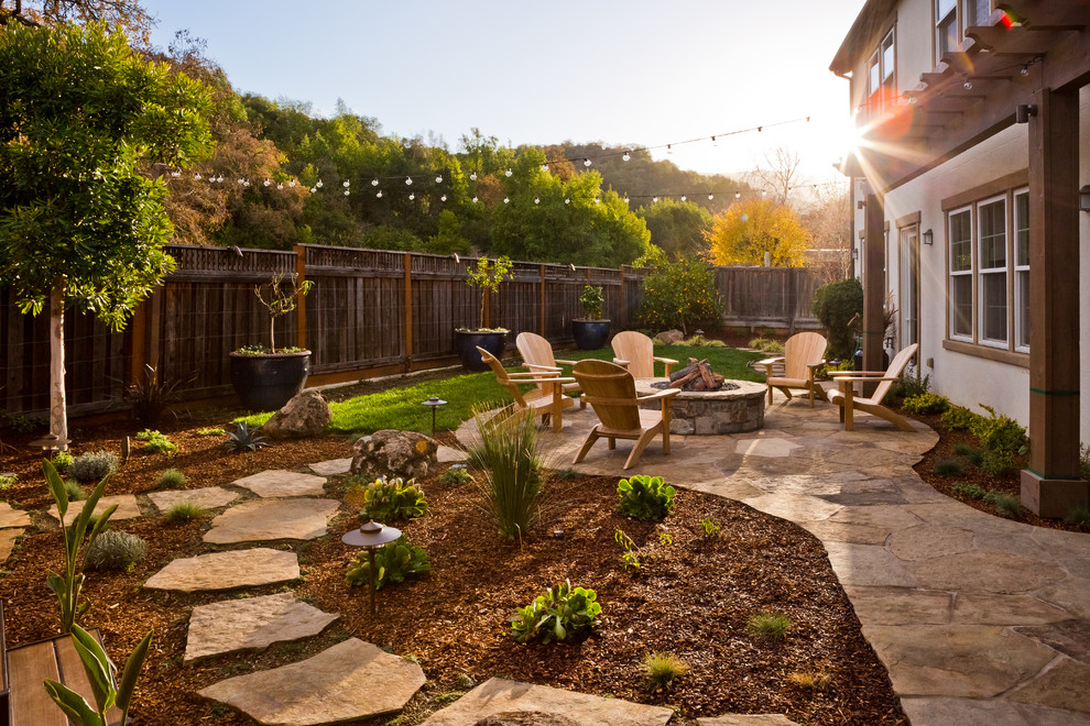 This is an example of a mid-sized country backyard full sun garden in San Francisco with a fire feature and natural stone pavers.