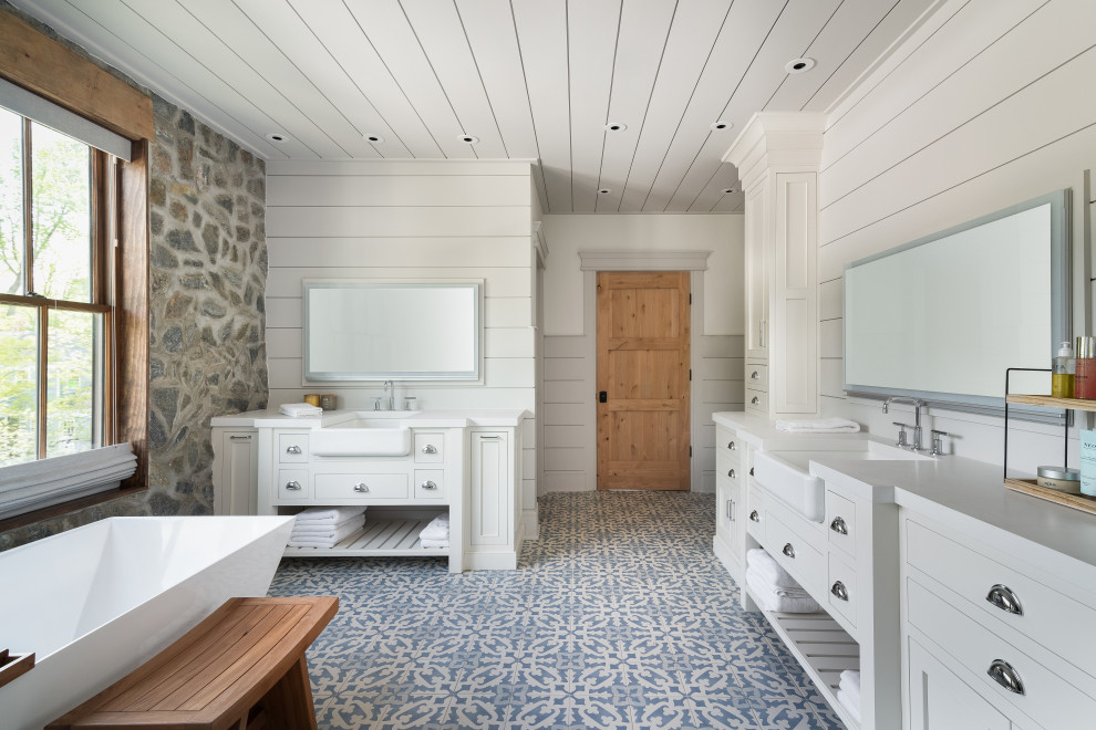 Lantlig inredning av ett stort vit vitt en-suite badrum, med luckor med profilerade fronter, vita skåp, ett fristående badkar, en öppen dusch, vita väggar, mosaikgolv, ett integrerad handfat, bänkskiva i kvarts och blått golv