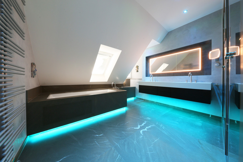 Geräumiges Modernes Badezimmer mit Whirlpool, Duschnische, Wandtoilette, grauen Fliesen, Marmorfliesen, grauer Wandfarbe, Marmorboden, Einbauwaschbecken, Mineralwerkstoff-Waschtisch, grauem Boden, Falttür-Duschabtrennung und weißer Waschtischplatte in München