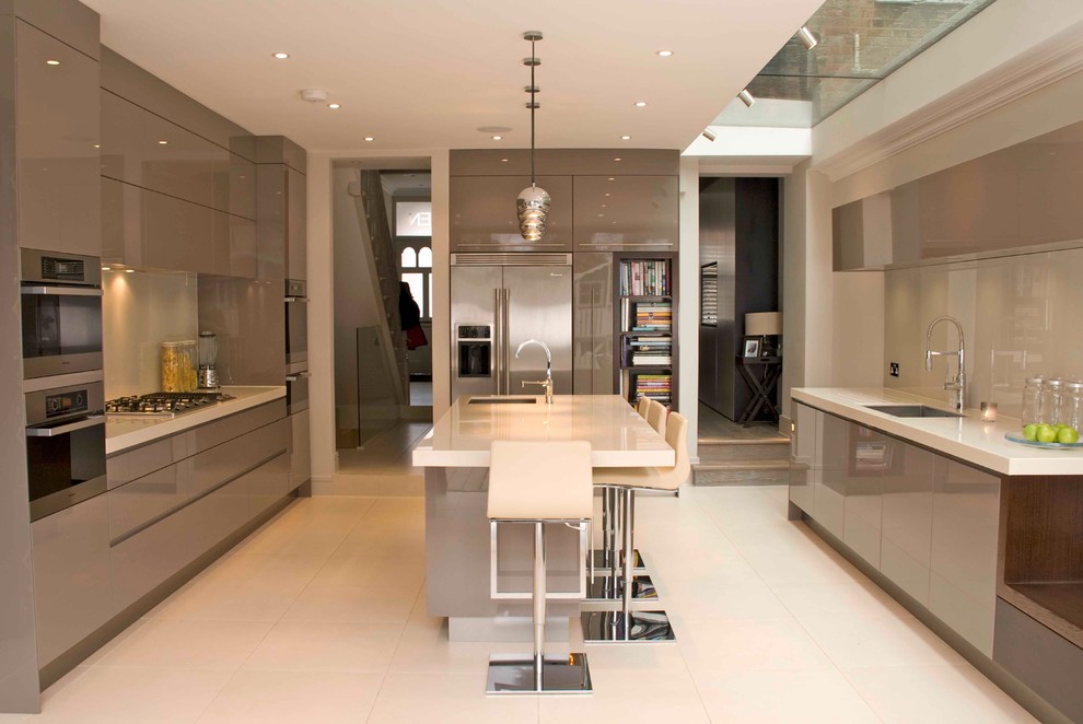 Design ideas for a large contemporary open plan kitchen in Cambridgeshire with an undermount sink, flat-panel cabinets, grey cabinets, solid surface benchtops, white splashback, glass sheet splashback, stainless steel appliances, limestone floors and with island.