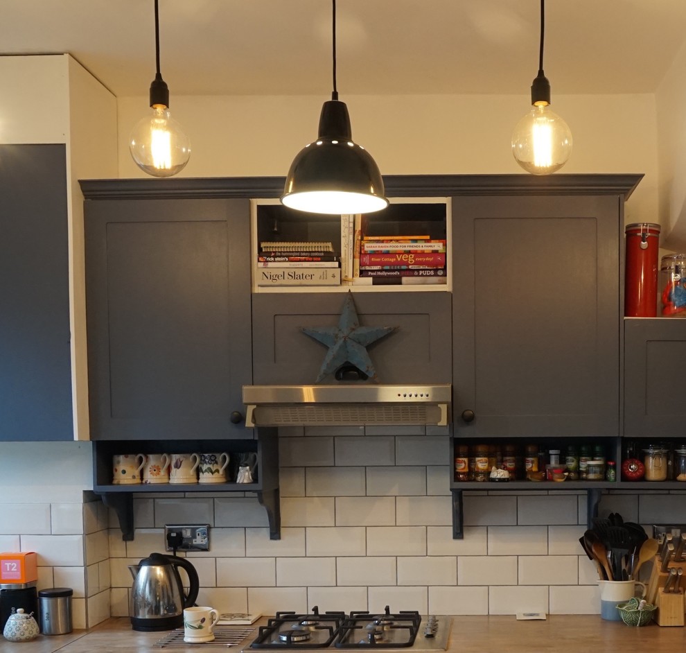 Inspiration for a small eclectic l-shaped eat-in kitchen in London with an integrated sink, shaker cabinets, blue cabinets, wood benchtops, white splashback, stainless steel appliances, dark hardwood floors, no island and subway tile splashback.