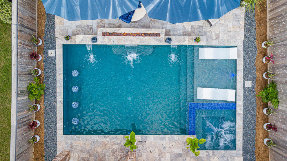 Esempio di una piscina tropicale rettangolare di medie dimensioni e dietro casa con pavimentazioni in pietra naturale