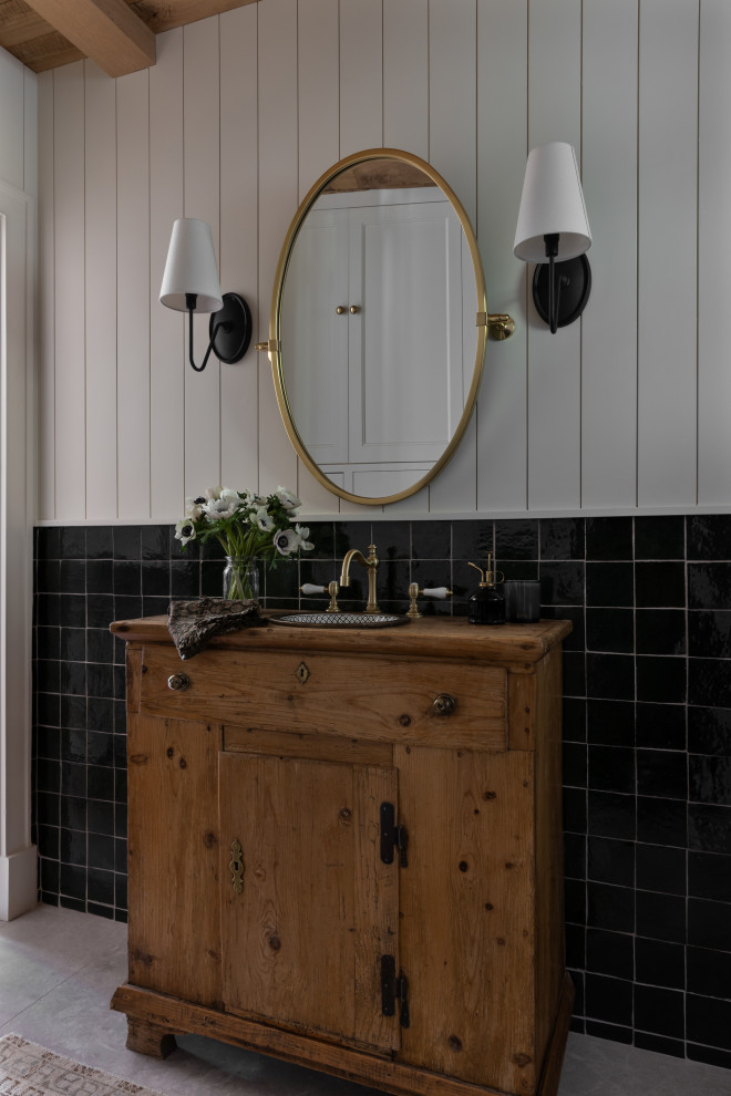 Example of a french country black tile gray floor, single-sink, exposed beam, wood ceiling and shiplap wall bathroom design in Austin with flat-panel cabinets, medium tone wood cabinets, white walls, a drop-in sink, wood countertops, brown countertops and a freestanding vanity