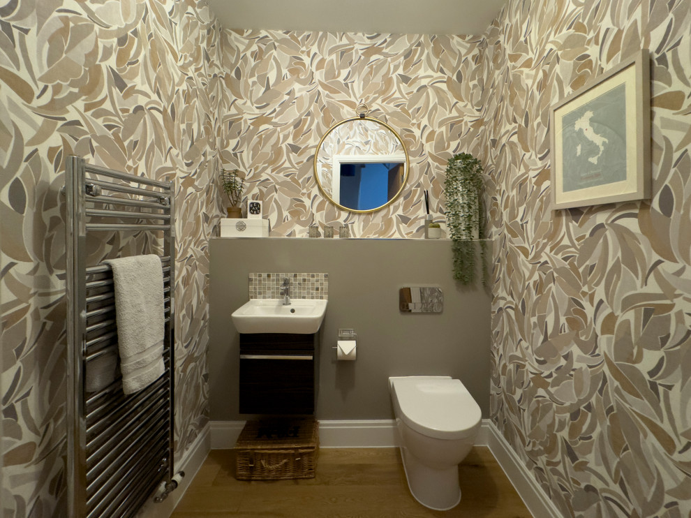Immagine di un bagno di servizio minimal di medie dimensioni con WC sospeso, parquet chiaro, mobile bagno sospeso e carta da parati